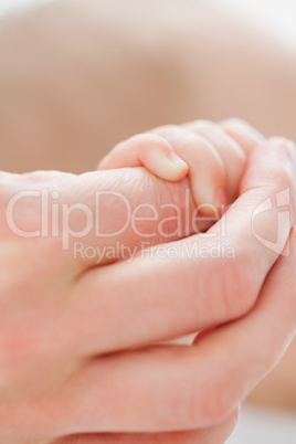 Hand holding the little hand of a baby