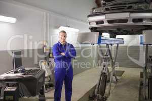 Smiling mechanic standing next to a car