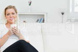 Woman on a sofa drinking a coffee