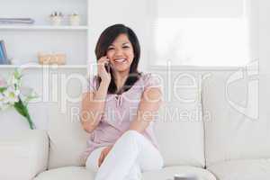 Laughing woman holding a phone and sitting on a couch