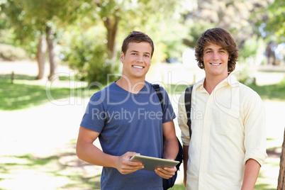 Close-up of two smiling male students with a touch pad