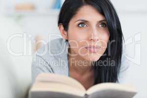 Woman with a book on her hands lying on a sofa