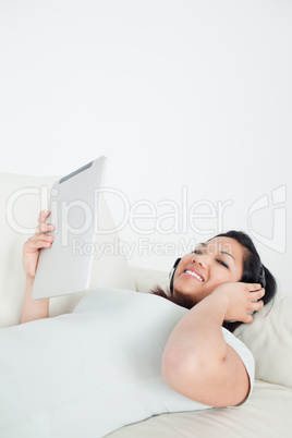 Woman lies on a sofa with headphones on and holding a tactile ta