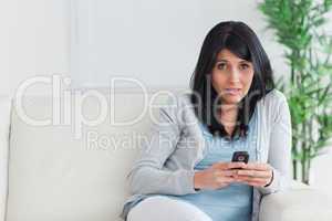Woman holding a phone while sitting on a couch