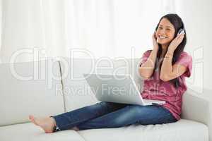 Smiling Latino student enjoying music on her sofa