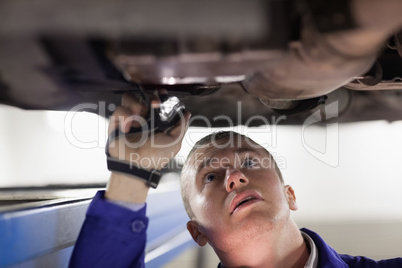 Mechanic illuminating the car with a flashlight