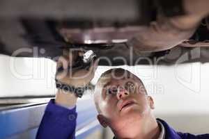 Mechanic illuminating the car with a flashlight