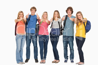 Smiling group giving a thumbs up as they wear backpacks