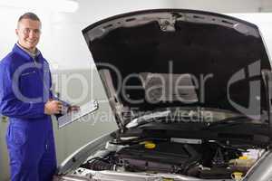 Smiling mechanic holding a clipboard