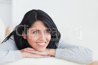 Smiling woman laying on a couch with her arms crossed under her