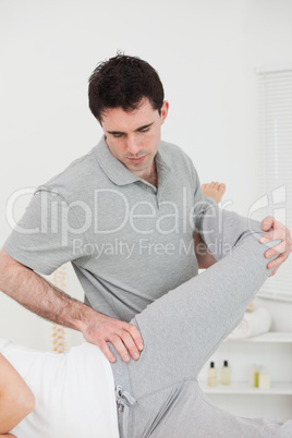 Physiotherapist standing behind a woman while stretching her leg