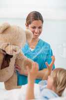 Smiling nurse showing a teddy bear to a child