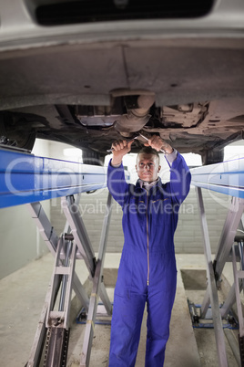 Mechanic standing while repairing the below of a car