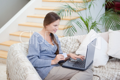 Women sitting on a sofa while using a laptop