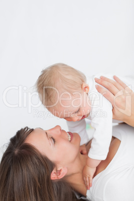 Smiling brunette woman playing with her baby