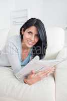 Woman lies on a couch and holds a magazine
