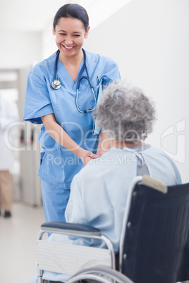 Nurse smiling while holding the hands of a patient