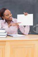 Black teacher holding a blank paper at desk