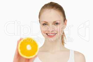Woman presenting an orange while smiling