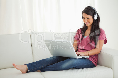 Latino student wears earphone using a laptop