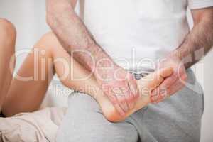 Reflexologist manipulating the foot of his patient while holding