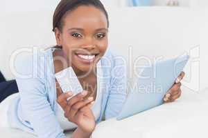 Black woman holding a tablet computer and a credit card