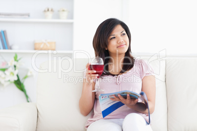Woman holding a magazine and a glass of red wine