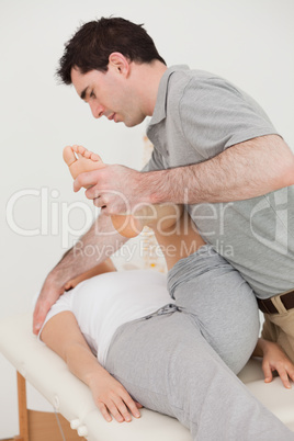 Serious osteopath stretching the leg of his patient Serious osteopath stretching the leg of his patient