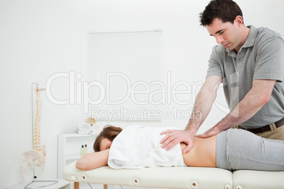 Serious practitioner massaging the lower back of a woman