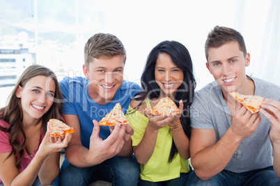 Friends about to eat their pizza as they look at the camera