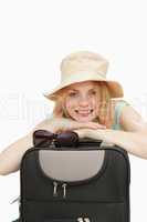 Smiling woman leaning on a suitcase