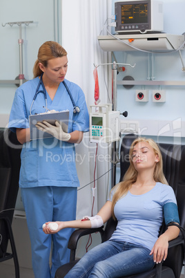Nurse holding a clipboard while looking at a patient