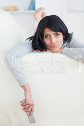 Sad woman on a sofa holding a television remote
