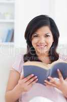 Woman sitting on a couch while she reads a book