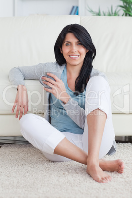 Woman sitting on the floor while holding a mug