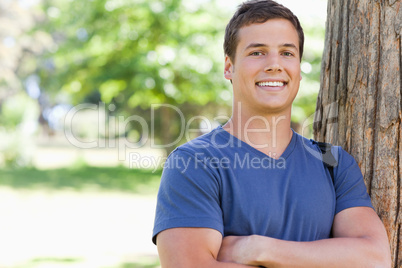 Portrait of a young man leaning against a tree