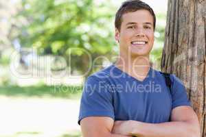 Portrait of a young man leaning against a tree