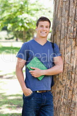 Portrait of a muscled student holding a textbook
