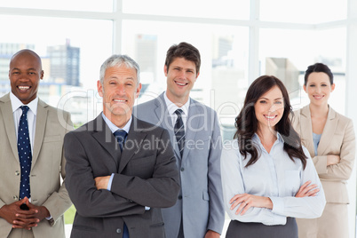 Five business people crossing their arms in front of a bright wi