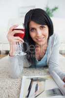 Woman smiling while holding a magazine and a glass of red wine