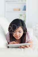 Woman touching a tablet while resting on a sofa