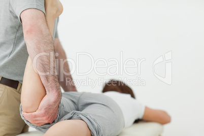 Woman lying forward while a man is stretching her leg