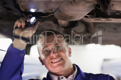 Mechanic looking at camera while holding a flashlight