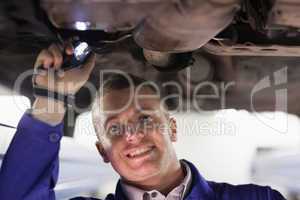 Mechanic looking at camera while holding a flashlight