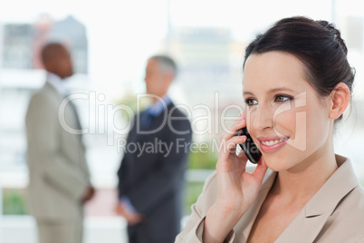 Young secretary talking on the phone while smiling and looking t