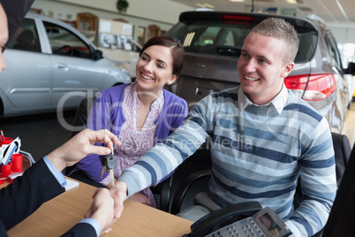 Happy couple shaking the hand of a salesman