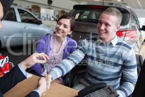 Happy couple shaking the hand of a salesman
