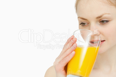 Woman drinking a glass of orange juice while looking away