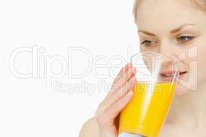 Woman drinking a glass of orange juice while looking away