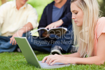 Close-up of a girl using a netbook while lying in a park